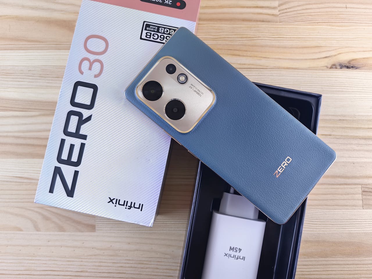 Mastering the First Impression: Your intriguing post title goes here Infinix Zero 30 smartphone with original packaging and accessories on a wooden surface.